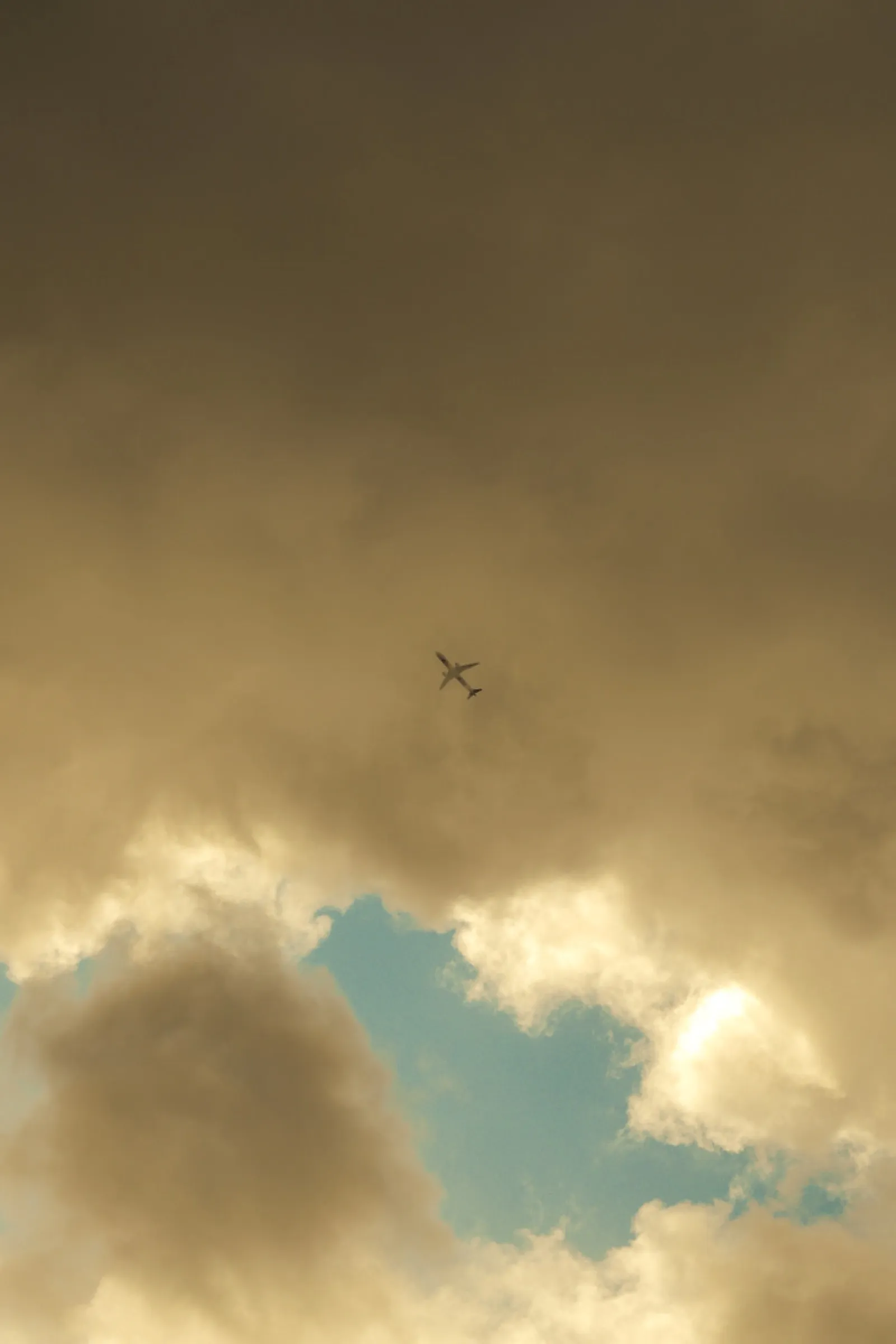 Airplane silhouette flying through dramatic cloudy sky