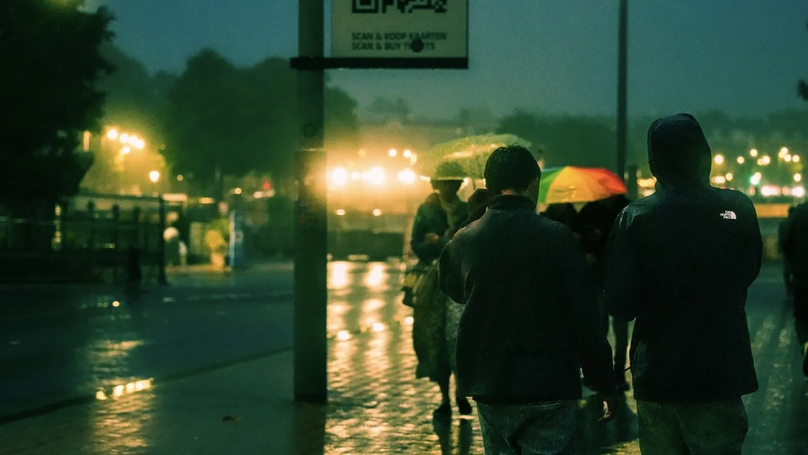 Rainy evening scene with people holding umbrellas