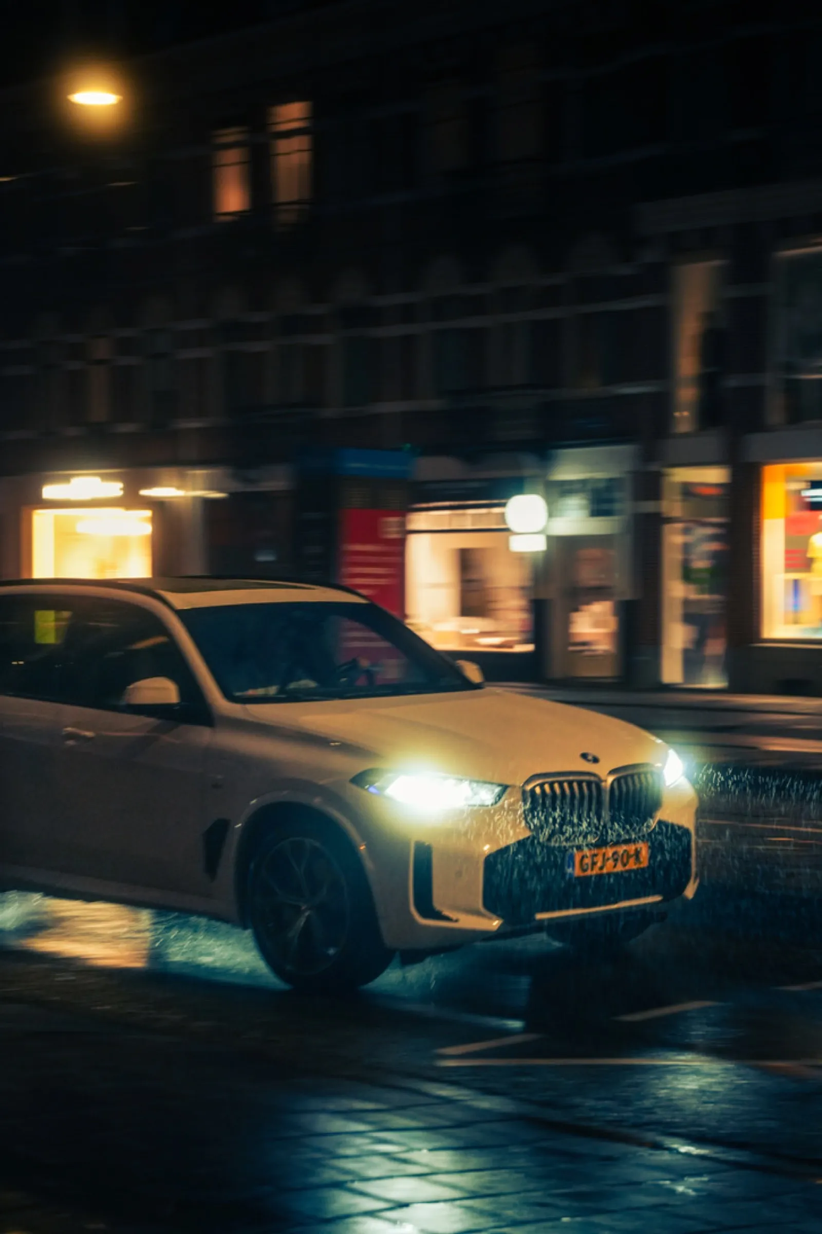Modern BMW parked on rainy Amsterdam street at night