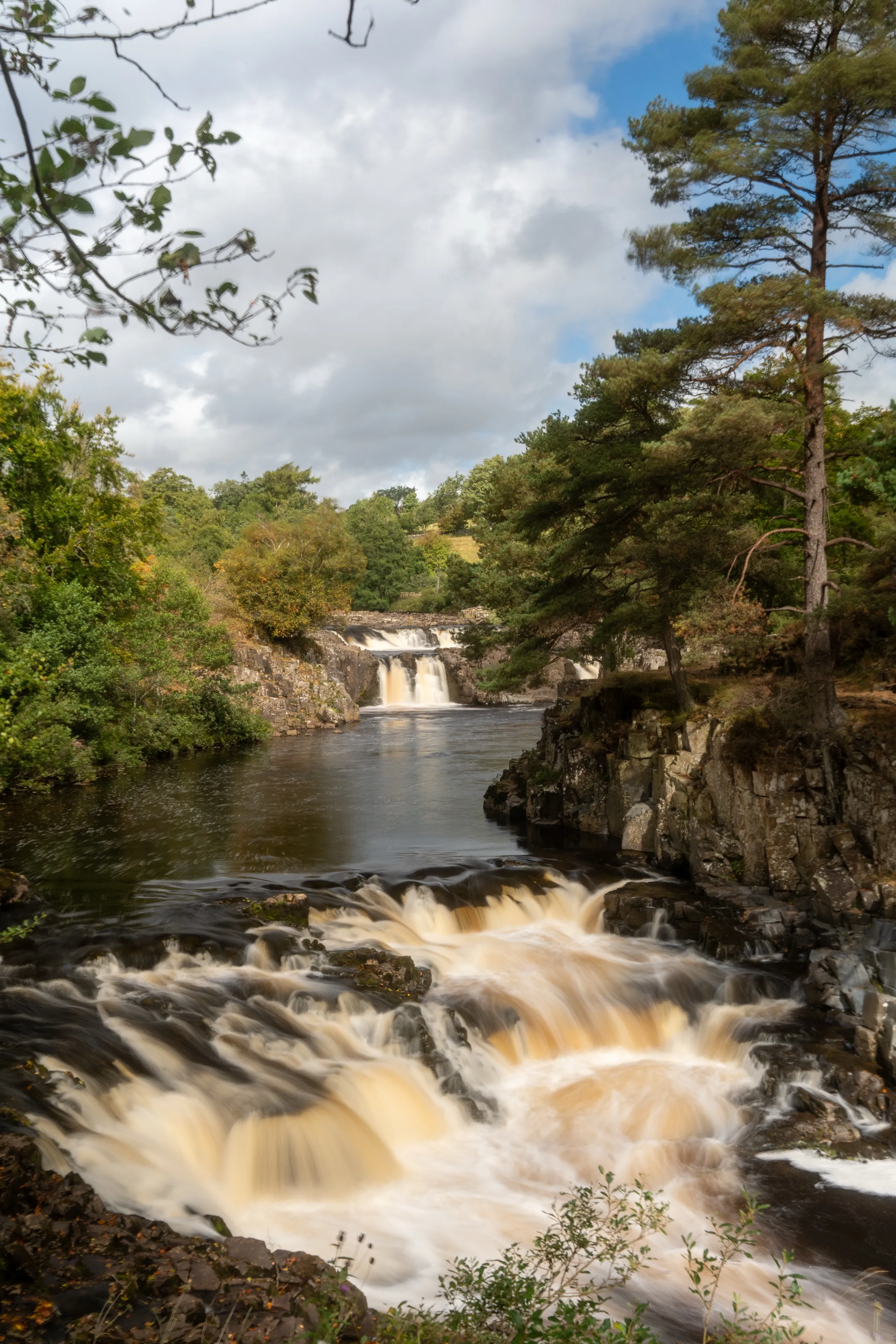 Waterfall with long-exposure flowing water and dramatic clouds