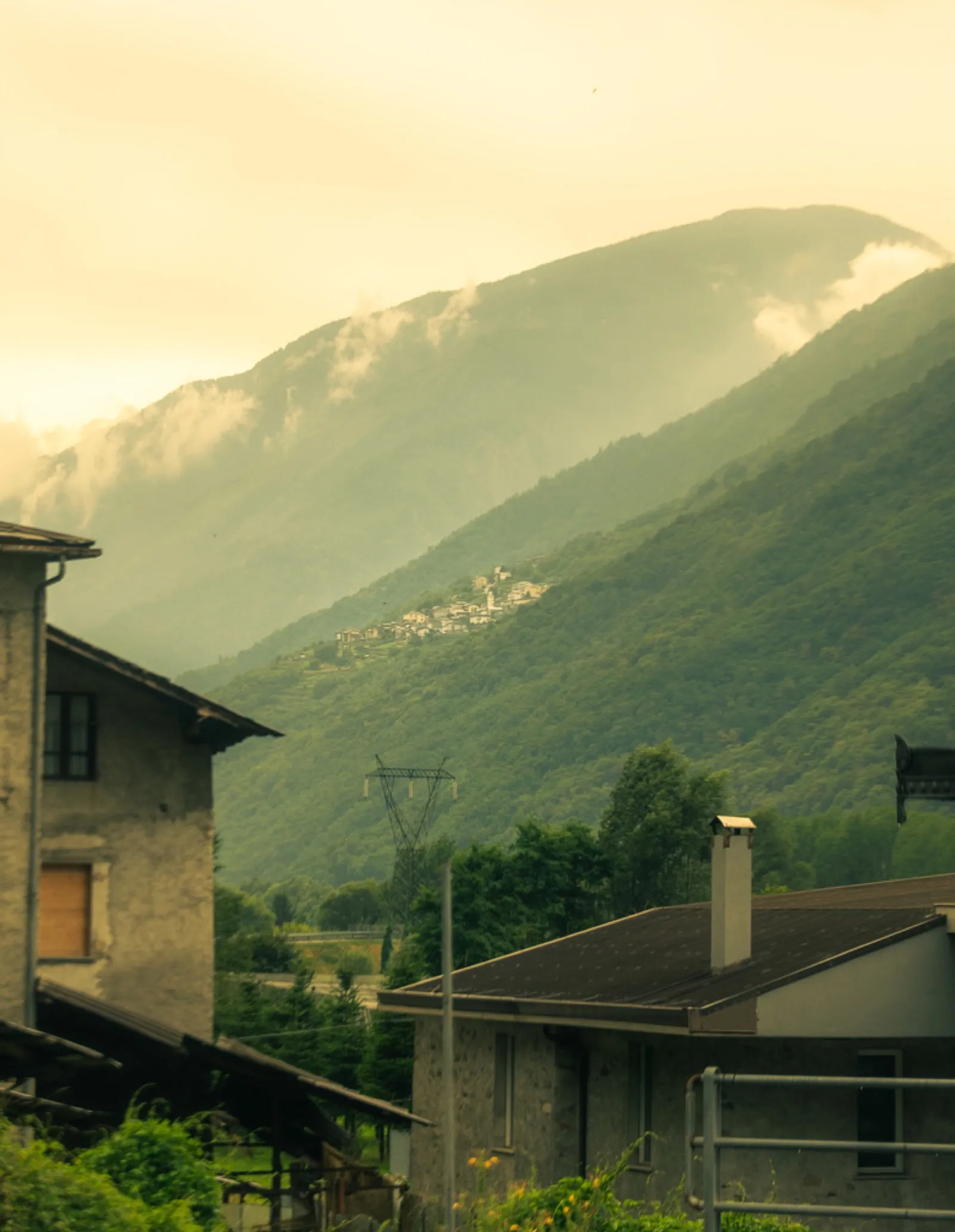 Misty green mountains with distant hilltop village