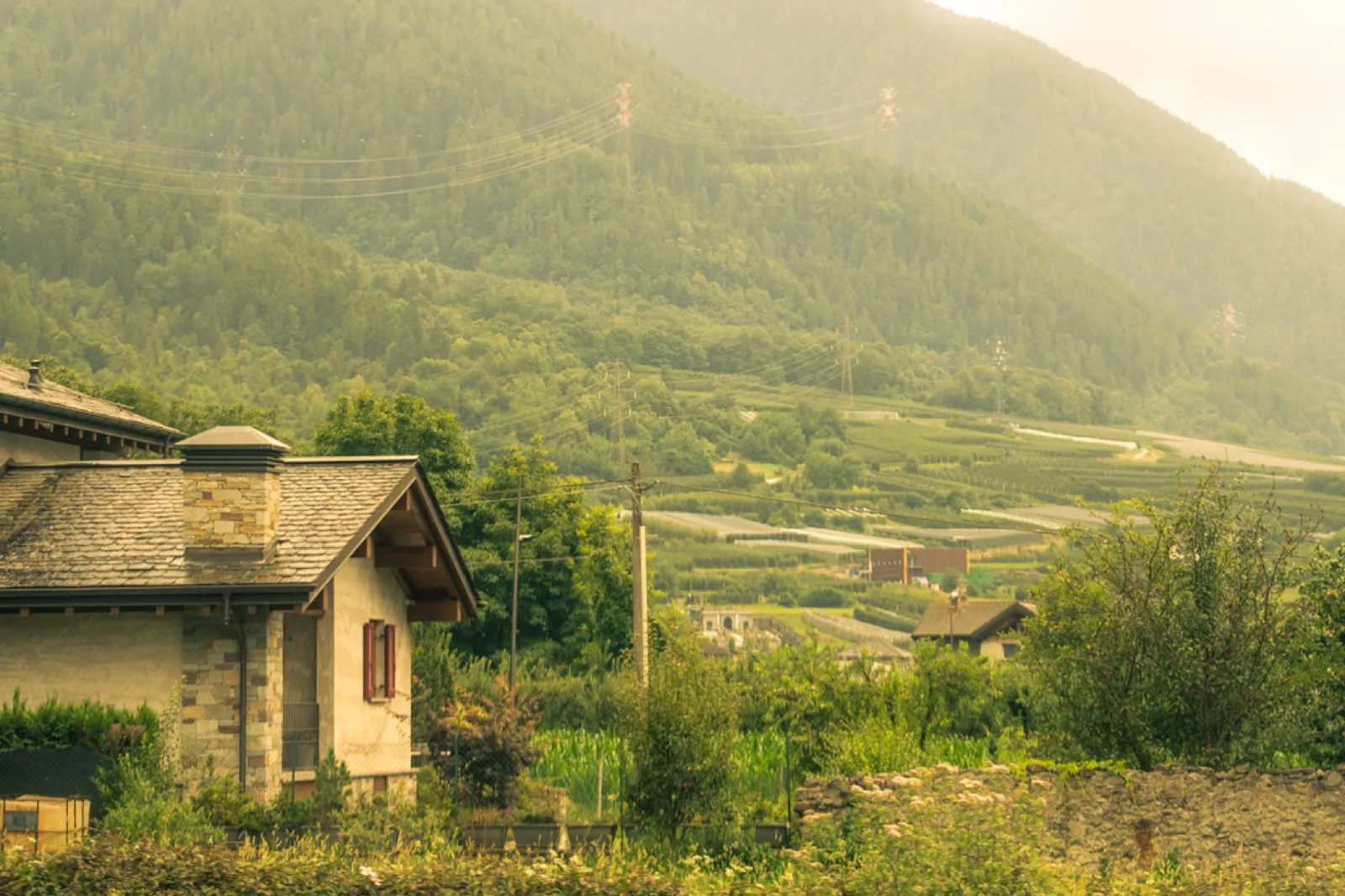 Rural stone house with mountain valley backdrop at sunrise