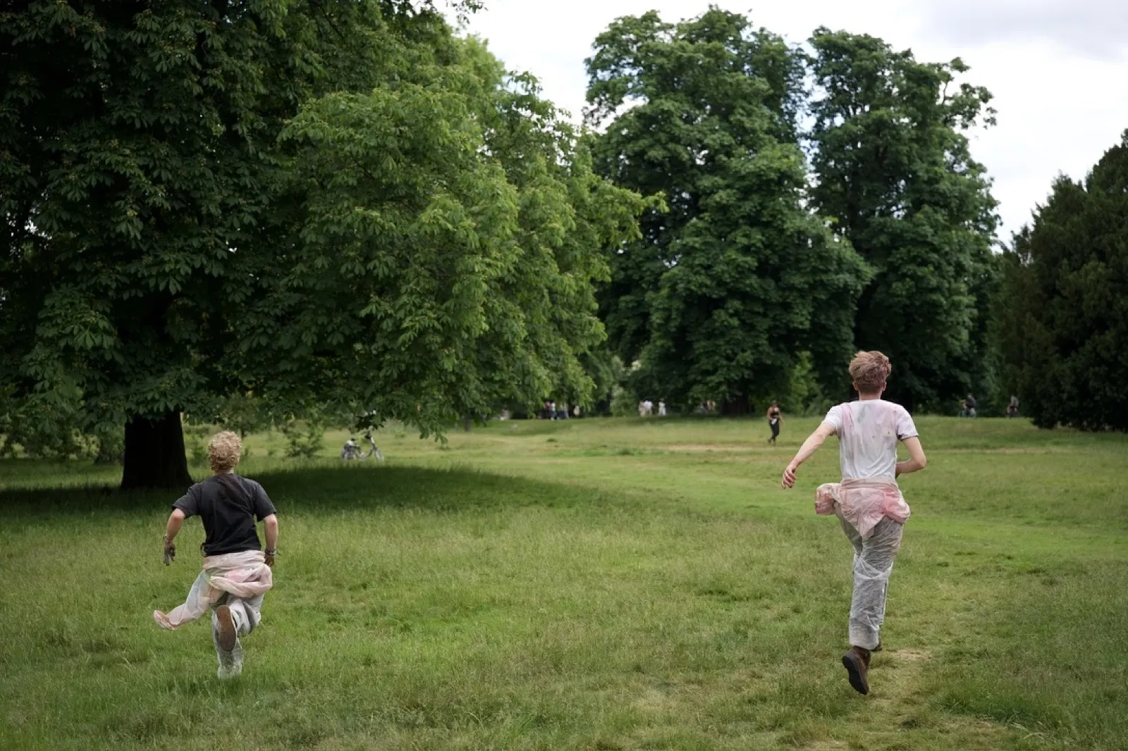 Two children running across green grassy park