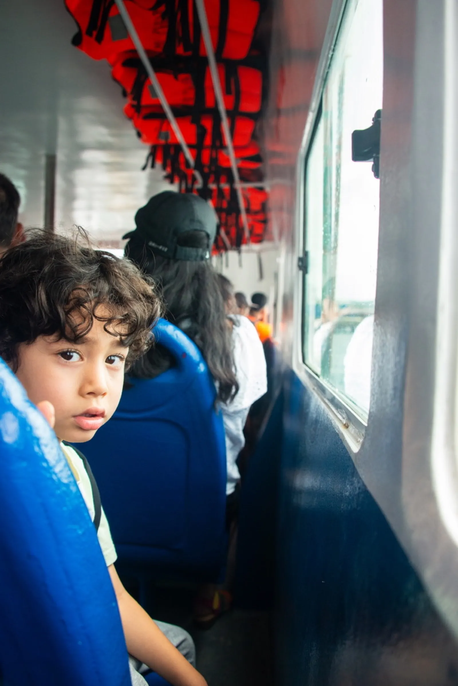 Young child in blue jacket looking out bus window