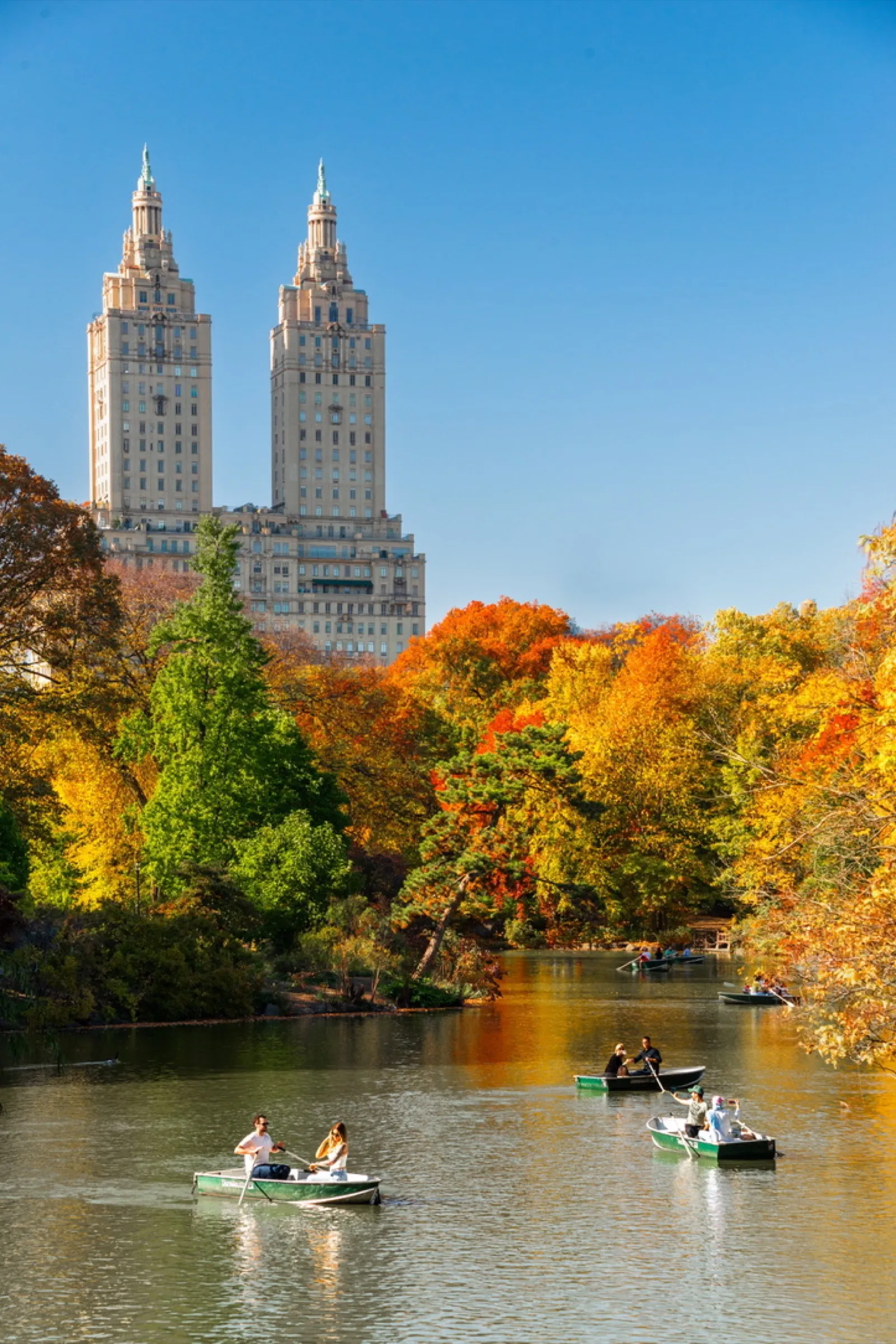 Twin towers rising above lake with colourful fall trees