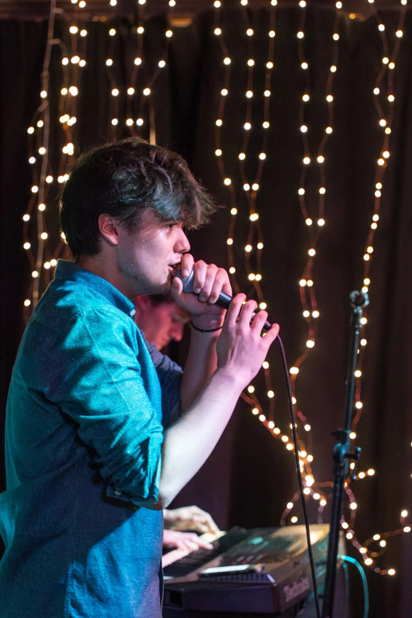 Singer with microphone and keyboard on illuminated stage