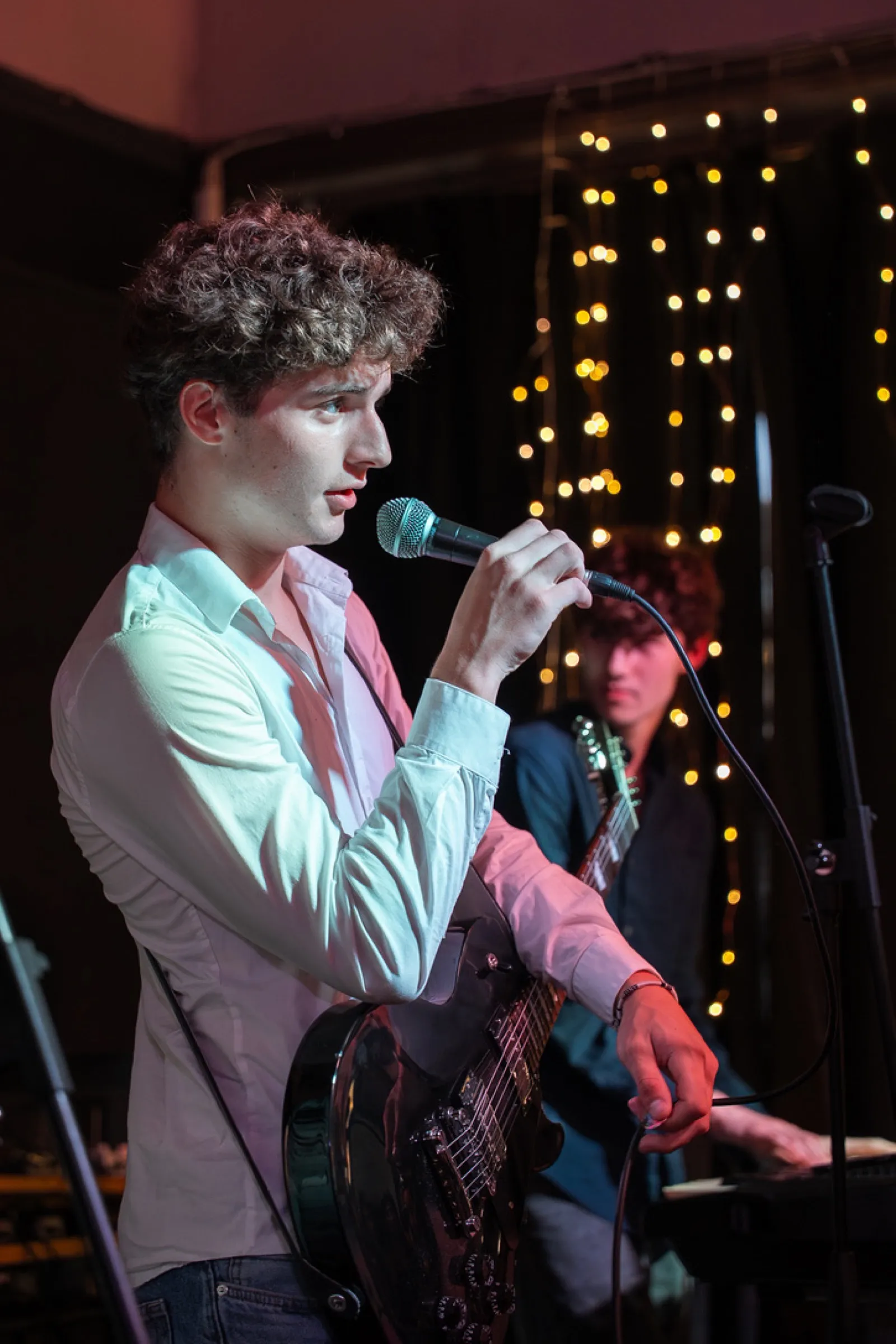 Lead singer with curly hair singing into microphone