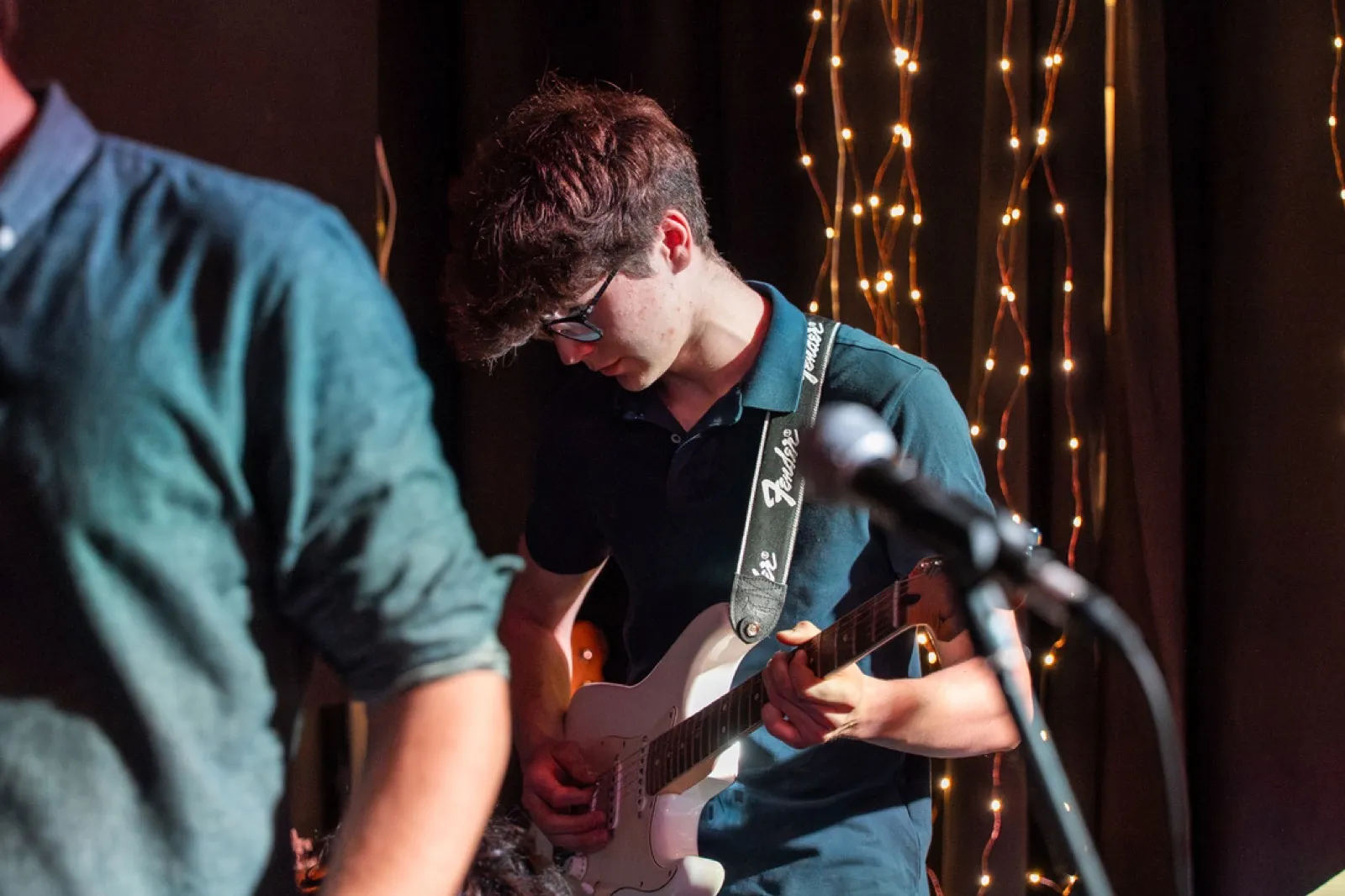 Two guitarists jamming with string lights backdrop