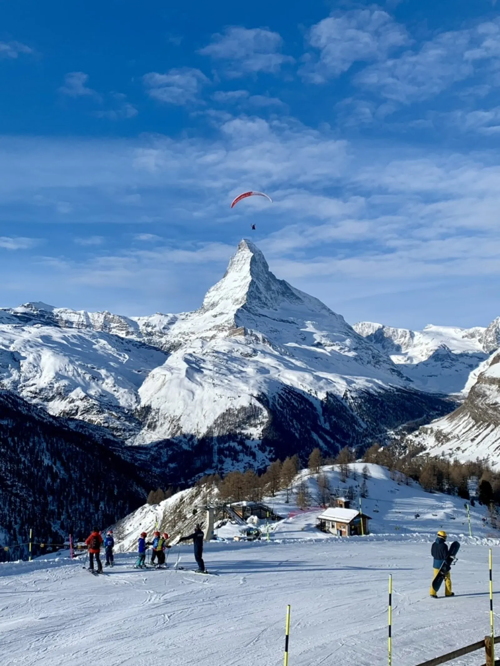 Paraglider flying over Matterhorn with ski slopes